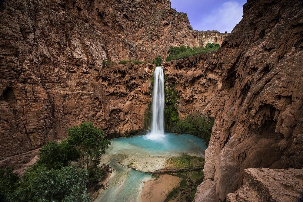 A waterfall surrounded by rock formations at Mooney Falls