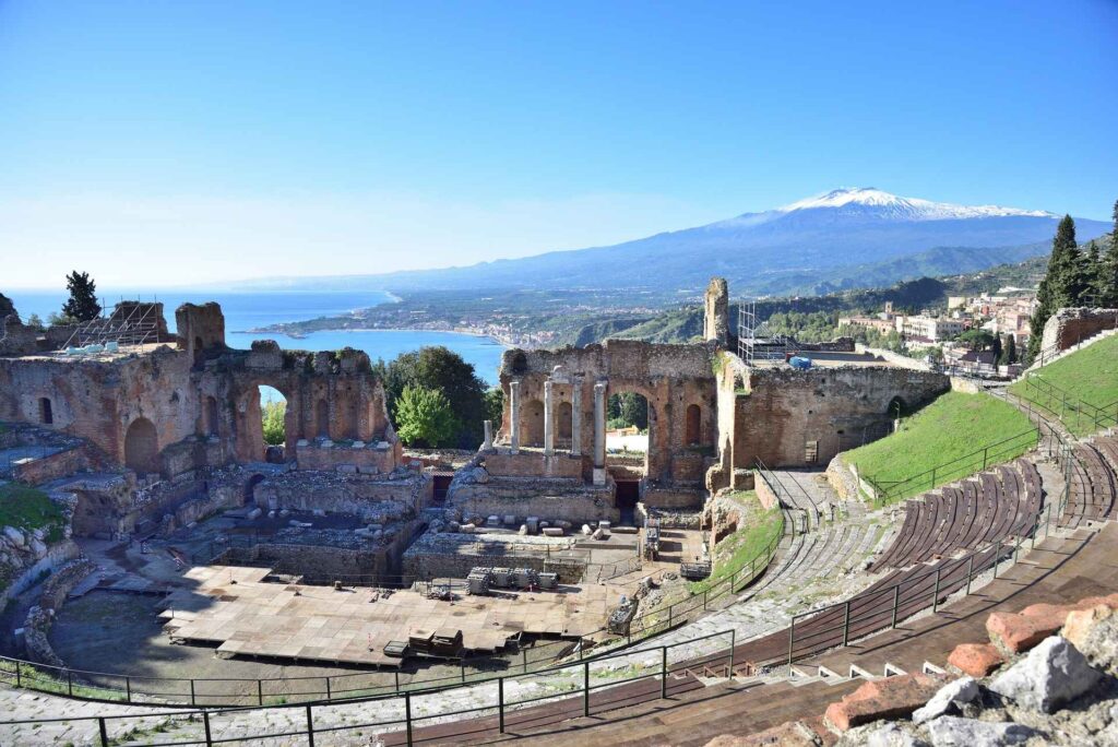 Ruins of the ancient Greek theater in Taormina, Sicily, with Mount Etna in the distance