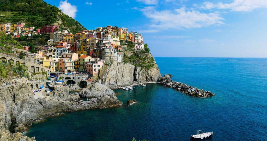Pastel houses of Manarola in Cinque Terre stacked on a cliff above the sea at sunset