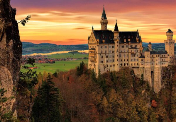 Neuschwanstein Castle at sunset above autumn forest in Bavaria.